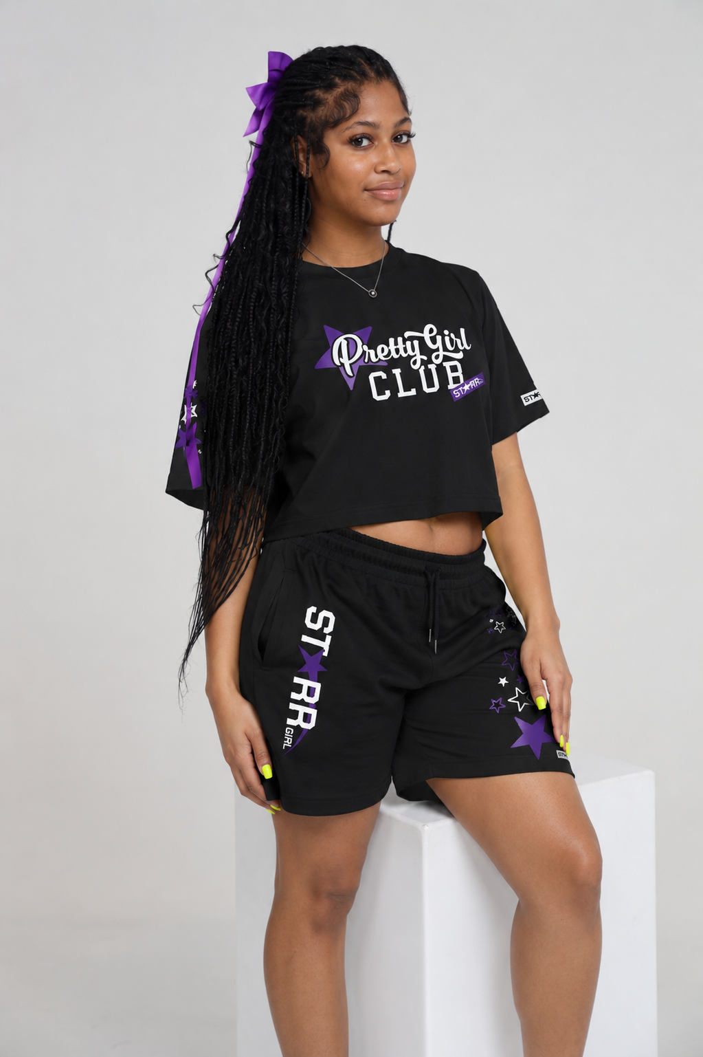 Starr Girls Pretty Girl Club Shorts in black and purple, shown in a lifestyle setting with fabric details and vibrant colors.