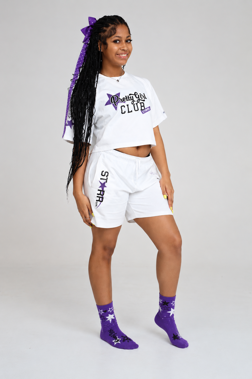 Starr Girls Pretty Girl Club Shorts in white and purple, shown in a lifestyle image with a purple and white color scheme.